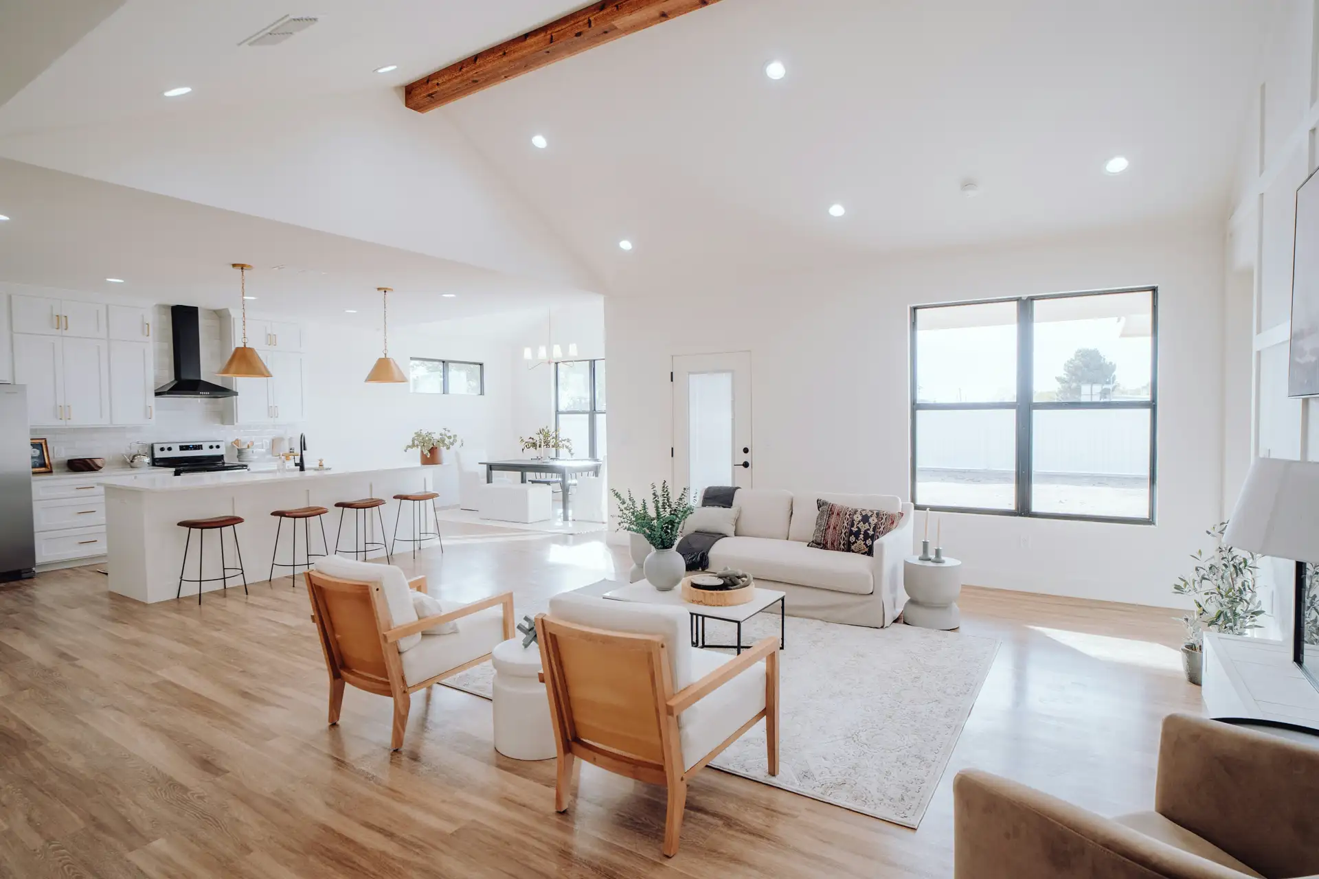 Open-plan great room lit by recessed LED can lights on a vaulted ceiling