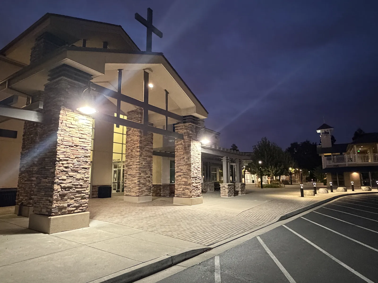 Church entry at dusk with new LED fixtures lighting the stone pillars and cross — North Creek Church, Walnut Creek